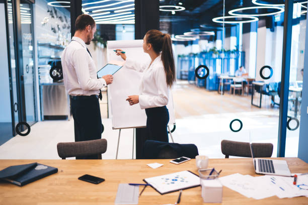 istock Professional economist using white board for writing ideas information for projectduring briefing with partner, successful business people collaborating together searching solutions in company 1440324195
