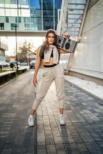 Young beautiful woman in hip-hop style with a boom box in the city