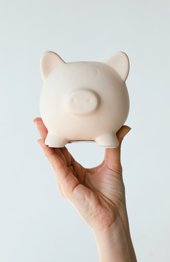 Woman holding piggy bank over white background.