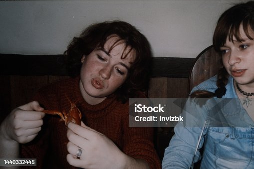 istock Two sisters are sitting at the cafe and one of them playing with cooked lobster. Vintage photo 1440332445