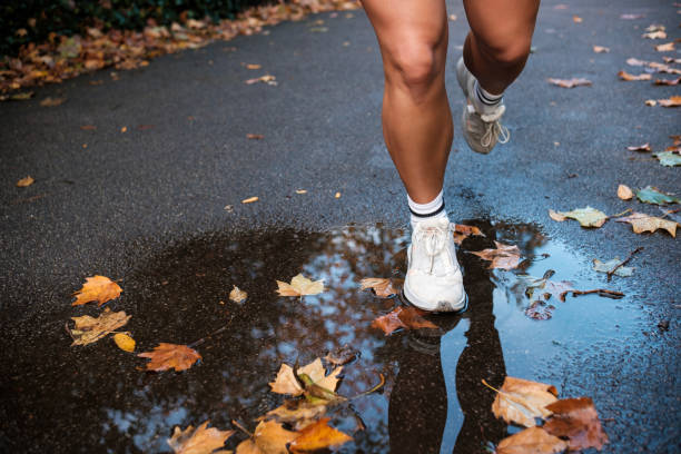 istock Strong woman legs running on autumn asphalt on a puddle. 1440332703