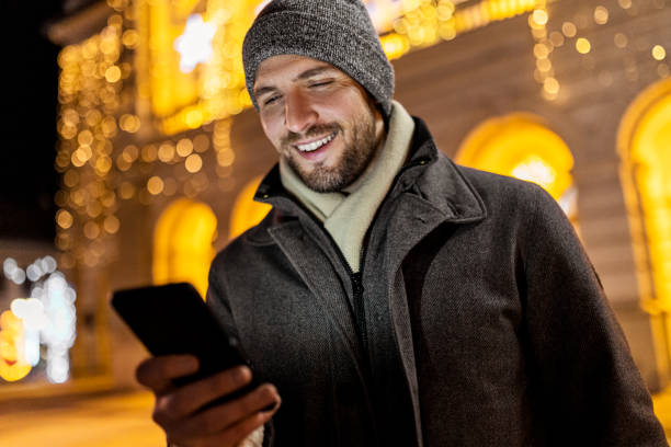 istock Smiling man messaging in city during Christmas 1440332931