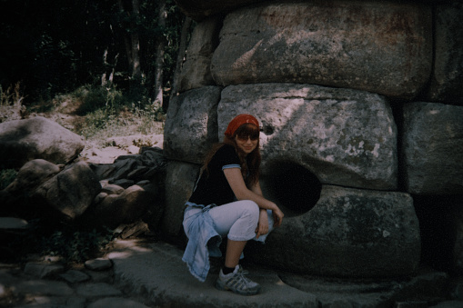 Vintage home photo of teenager girl next to the stone