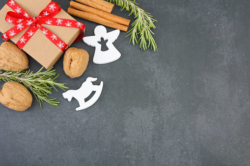 Christmas gift, cinnamon sticks, walnuts, rosemary and Christmas decoration on dark background