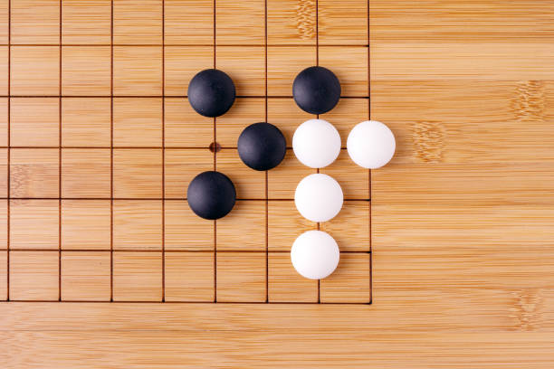 istock white and black stones lie on a wooden board for playing Go 1440334038
