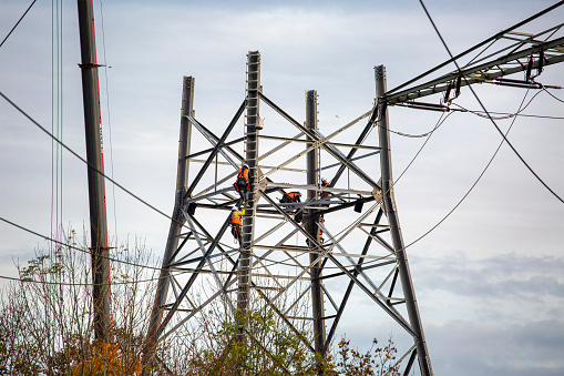 Sindlingen, Germany - November 08, 2022: Workers assemble a pylon for electricity transmission near Sindlingen in Germany. Proportion of renewable energy sources used in electricity generation in Germany is currently increasing much faster than the necessary grid expansion to transport it, therefore Germany is expanding its national power grid as a necessary infrastructure measure.