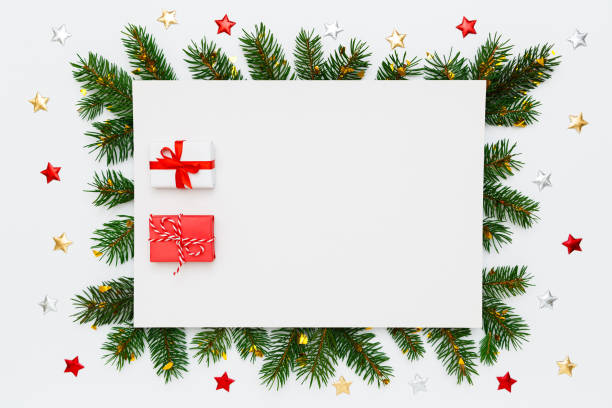 istock Christmas, New Year holiday layout with copy space. Blank white paper with two small Christmas gifts in frame of natural fir tree branches and decorations on white flat lay background. 1440337982