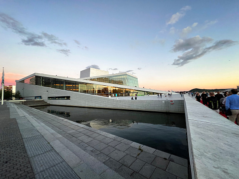 August 27, 2022 - Oslo, Norway.  Visitors to the city enjoy an evening stroll near the Opera House and Oslo fjord.