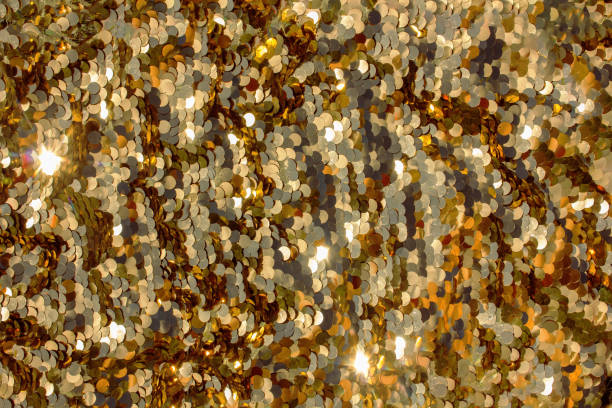 Shiny gold background with iridescent sparkles, sequins. Festive background.