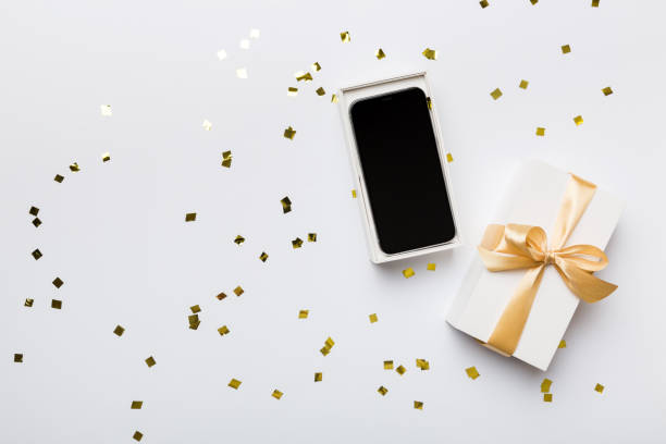 istock Opened gift box with gold ribbon and smartphone on color background, top view. Blank open box packaging mockup , Template for your design - branding mockup 1440346096