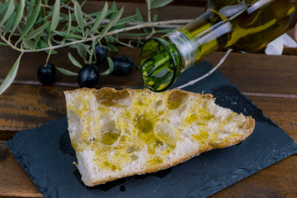 pouring olive oil from an oilcan onto toasted bread stock photo