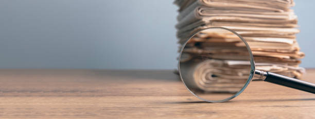 istock Pile of papers and a magnifying glass 1440350422