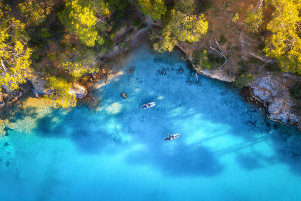 青い海の上に浮かぶサプボード上の人々の空中写真、岩、夏の日没時の木々。ブルーラグーン、オルデニズ、トルコ。熱帯の風景。澄んだ水の上のカヤック。アクティブな旅行。カヌーのト� - kayaking kayak sea coastline ストックフォトと画像