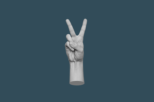 Female hand showing a peace gesture isolated on a dark teal blue color background. 3d trendy collage in magazine style. Contemporary art. Modern design. Victory hand sign