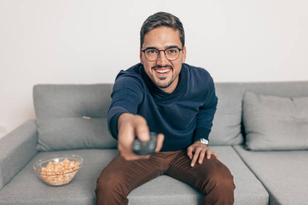 istock Man holding remote control to change the channel 1440358291