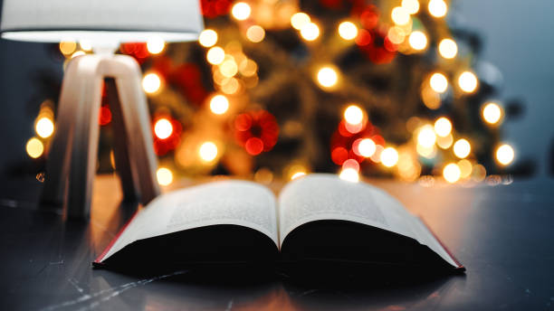 istock Open book on a table in front of Christmas tree during night 1440358598