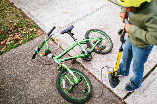 мальчик накачивает велосипедную шину с велосипедным насосом - bicycle bicycle pump inflating tire стоковые фото и изображения