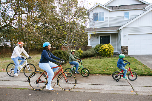 A young African American family enjoys a fun time of family exercise, riding bikes together on a cool Autumn day.  Healthy lifestyle and good childhood memories.