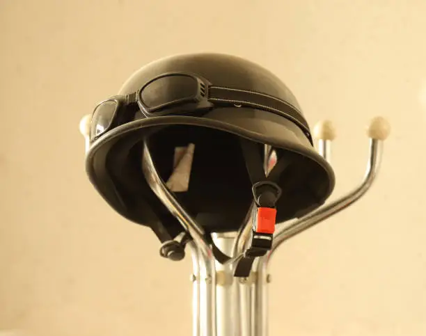 Photo of Motorcycle black helmet with wind protection goggles hung on a hanger