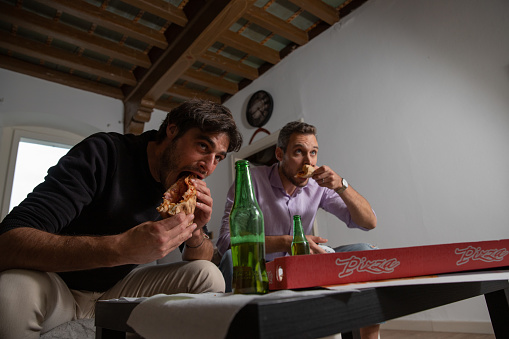 Happy friends gamers take a beak during video game match, it's pizza time.