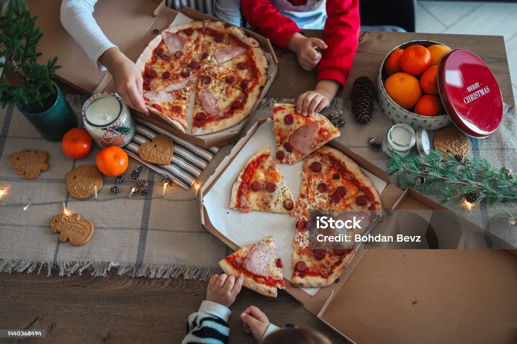 Happy children eat pizza, christmas dinner. The concept of a culinary New Year's master class Happy children eat pizza, christmas dinner. The concept of a culinary New Year's master class. Delivering Stock Photo