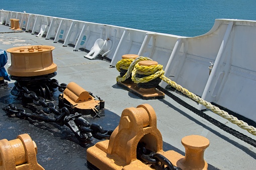 View on forward manoeuvring station on cargo container vessel with black and yellow painted bollards, mooring roller and column for remote control of mooring winch sailing through Mediterranean sea.