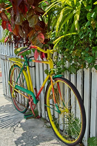 Colorful old bicycle and white picket fence at the corner of Fleming and Frances street in Key West Florida. Lush colorful vegetation and this old bike provide charm to the harsh light of the Florida keys.
