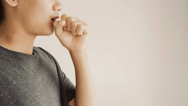 Close up of teen boy coughing from cold and flu,COPD, pneumonia, bronchitis, asthma, allergy, respiratory illness concept stock photo