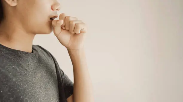 Close up of teen boy coughing from cold and flu,COPD, pneumonia, bronchitis, asthma, allergy, respiratory illness concept