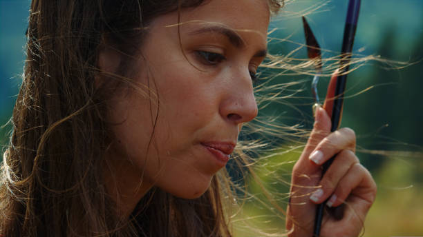 istock Creative painter biting lip windy day. Closeup girl holding paint tools in hand 1440381288