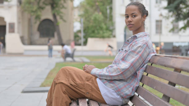 istock African Woman Looking at Camera while Sitting on Bench 1440381802