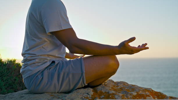 istock Guy relaxing lotus position in evening ocean sunlight. Unknown yogi meditating 1440383494