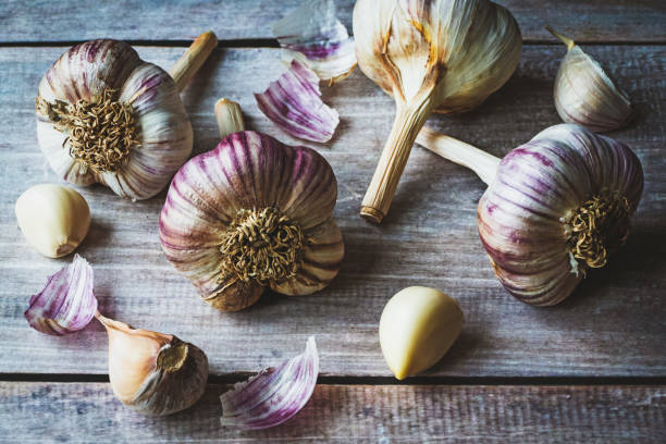 Garlic bulbs and cloves on wooden table background Garlic bulbs and cloves on wooden table background growing garlic stock pictures, royalty-free photos & images