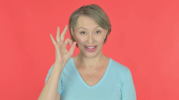 istock Old Woman with Ok Sign on Red Background 1440387869