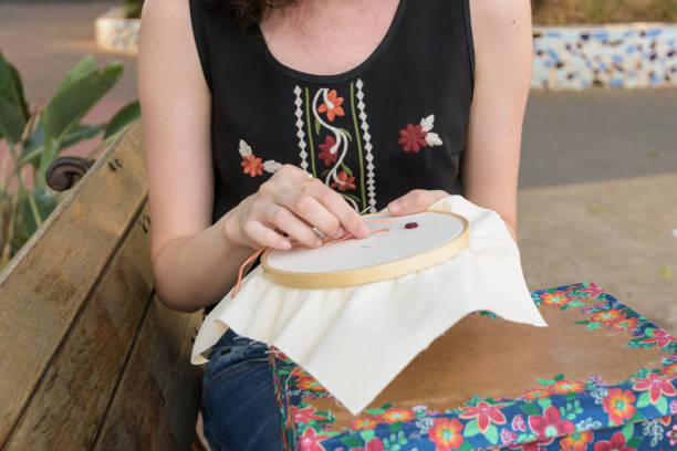 jovem costurando um bordado em uma praça - appliqué - fotografias e filmes do acervo