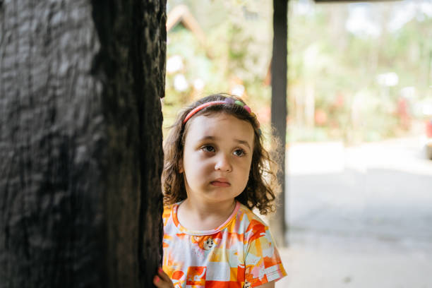 Portrait of adorable little fashionable 7 years old girl leaning on the vintage wooden door with Chinese trumpet creeper in the background