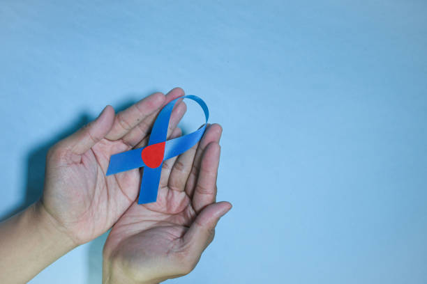 istock Blue ribbon awareness with red blood drop in man hands 1440398073