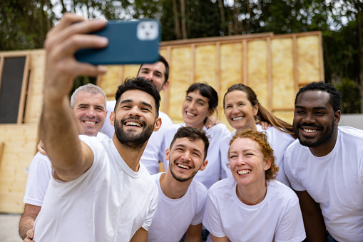 Happy group of Latin American volunteers talking a selfie while working on a construction project