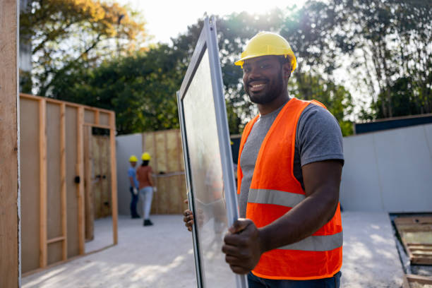 istock Happy construction worker carrying a window at a building site 1440404380