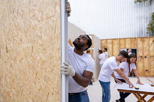 African American volunteer installing a window while building a house for charity