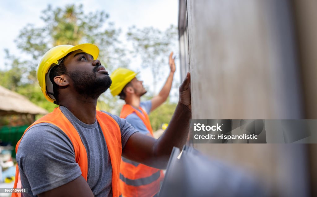 Construction workers installing panels while building a manufactured house Team of construction workers installing panels while building a manufactured house - construction industry concepts Occupation Stock Photo