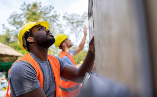 Construction workers installing panels while building a manufactured house stock photo