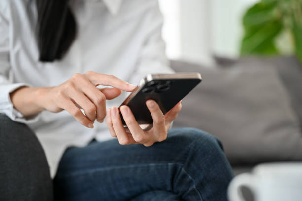 istock cropped, A female using her smartphone, typing on screen, holding her mobile phone. 1440404950