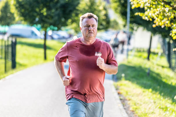 Mid adult man exercising, jogging in road, medium shot. Healthy lifestyle, person in sportswear running in street, doing sports outdoors, front view