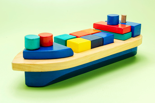 A colorful wooden toy ship on a colored background