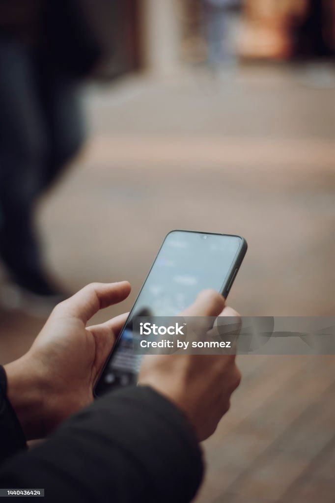 young person holding a smartphone on the street Connection Stock Photo