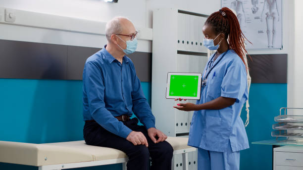 istock Nurse showing tablet with greenscreen display to senior man 1440438168