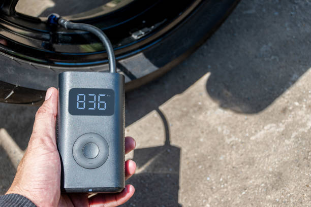 Hand holding a portable inflator is inflating a motorcycle tire.