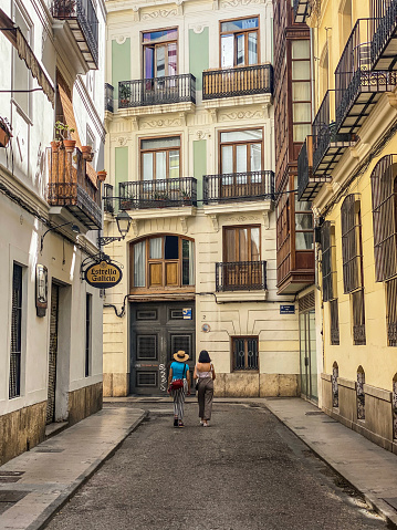 Valencia, Spain - September 20, 2020:  Rear view of two female tourists walking in downtown Valencia. During the coronavirus pandemic the number of tourists in the city got reduced to a minimum due to travel restrictions