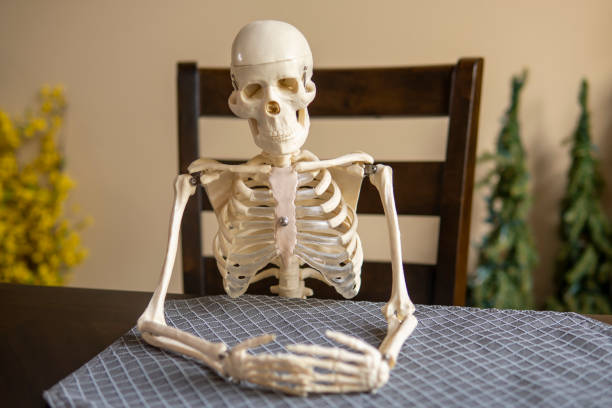 istock Skeleton sits alone at table in the room. Loneliness concept 1440442300